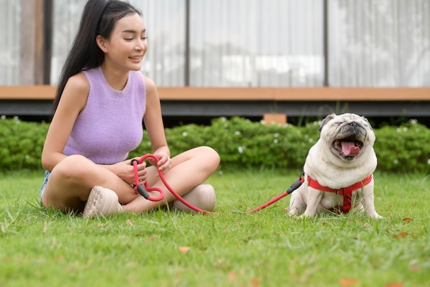 Une femme asiatique heureuse jouant avec un chiot mignon et intelligent dans le jardin.