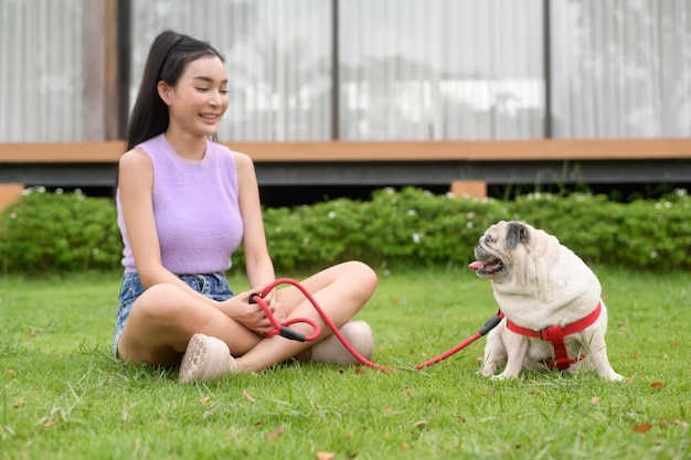 Une femme asiatique heureuse jouant avec un chiot mignon et intelligent dans le jardin.