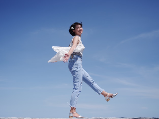 Femme asiatique heureuse et sourire sur la plage et le ciel bleu