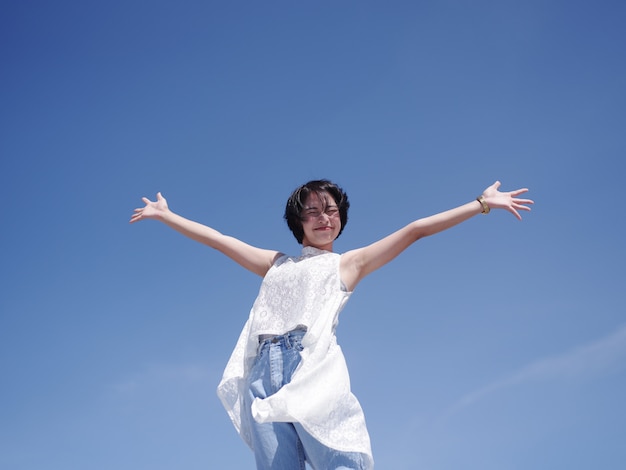 Femme asiatique heureuse et sourire sur la plage et le ciel bleu