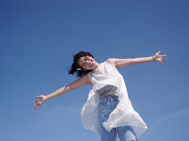 Femme asiatique heureuse et sourire sur la plage et le ciel bleu