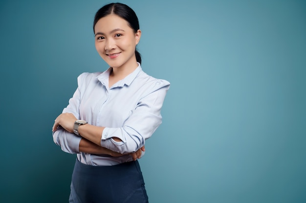 Femme asiatique heureuse surprise posant sur bleu.