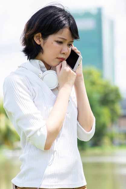 Femme asiatique inquiète faisant un appel téléphonique dans le jardin