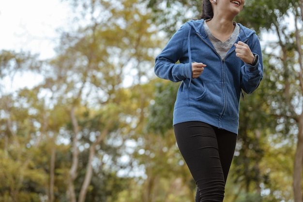 La femme asiatique jogging courir sur la route en plein air. Parc naturel. Concept sain et mode de vie.