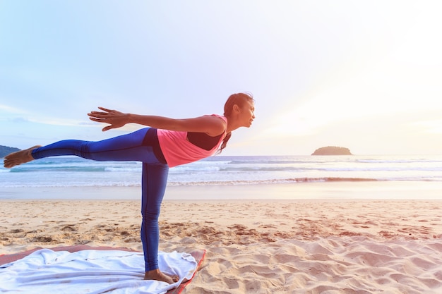 Femme asiatique jouant au yoga et exercice sur la plage tropicale en Thaïlande