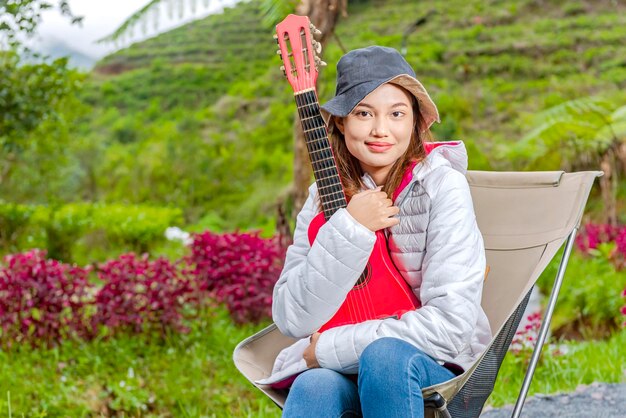 Femme asiatique jouant de la guitare profitant de l'activité du camp