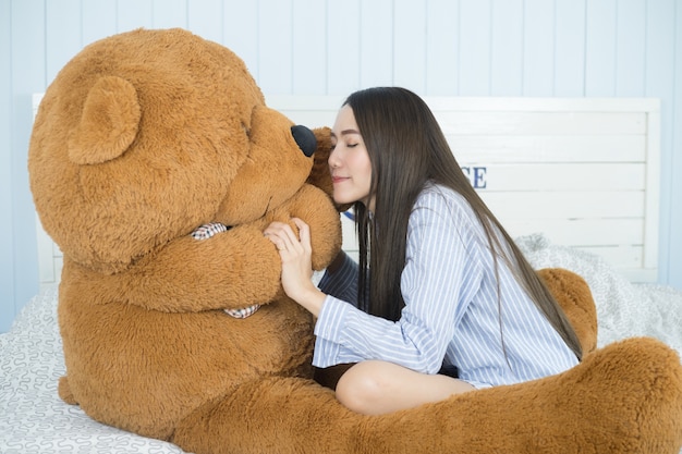 Femme asiatique jouant avec des ours en peluche dans la chambre à coucher.