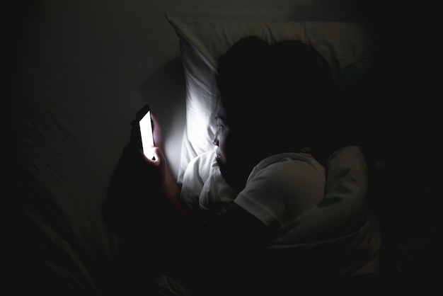 Une femme asiatique joue au smartphone dans le lit la nuitThailand peopleaddict news about COVID19 Jusqu'à ce qu'elle ne puisse pas dormir