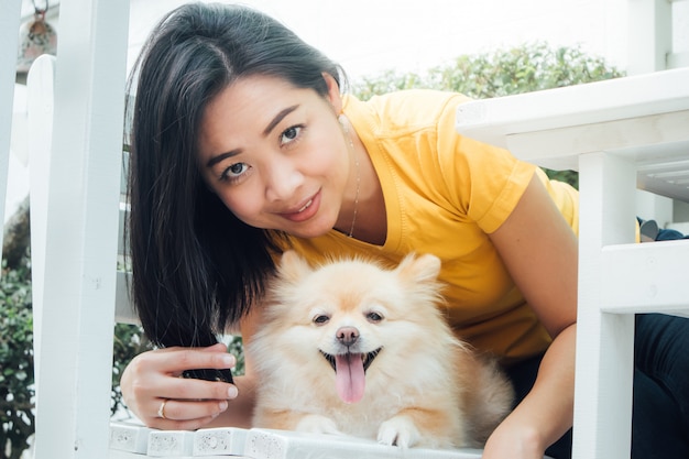 Femme asiatique joue avec son chien poméranien.