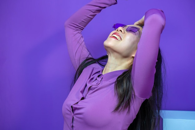 Photo une femme asiatique joyeuse lève les mains, les bras souriants, heureuse, isolée sur un fond violet violet.