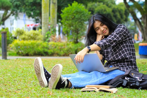 femme asiatique joyeuse travaillant à distance sur un ordinateur portable réunion d'appel vidéo et lire un livre en regardant la caméra