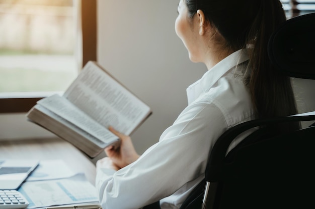 Femme asiatique lisant un livre assis au café ou au bureau à domicilexA