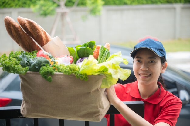 Femme asiatique livrer un sac de nourriture, donner au client devant la maison