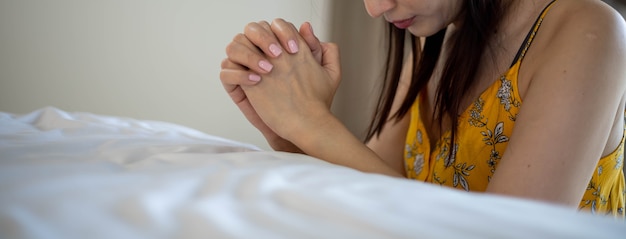 Femme asiatique avec la main en prière, les mains jointes en prière sur le lit. Concept pour la foi, la spiritualité et la religion.