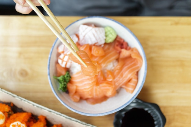 Femme asiatique mangeant du sashimi de tranche de saumon avec du riz dans un restaurant japonais