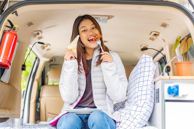 Femme asiatique mangeant son petit déjeuner à l'intérieur du camping-car