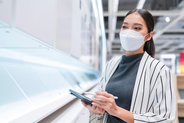 Femme asiatique avec masque facial propriétaire d'entreprise main utiliser tablette vérification inventaire stock idées de stratégie de planification d'entreprise conceptasian femme vérification stock au fond de la boutique de détail