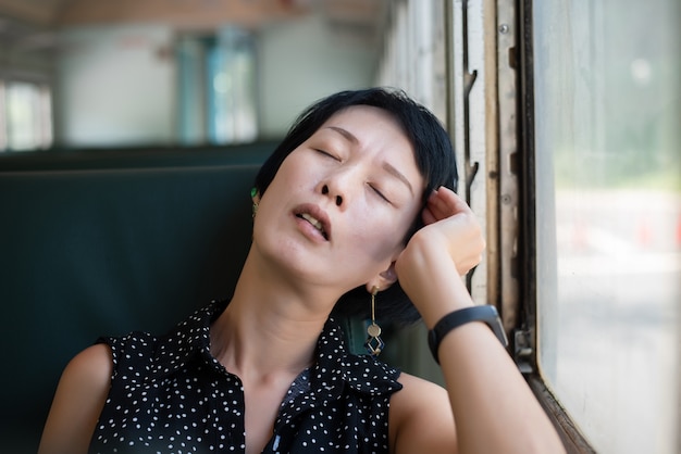 Une femme asiatique mature dort dans le train