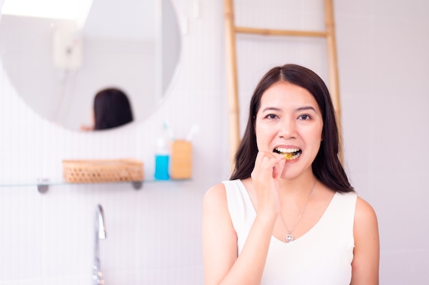 Femme asiatique mettant des dents d'accolades ou un entraîneur de silicone, orthodontie, concept de santé dentaire, dent cariée