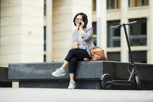 Femme asiatique moderne, parler, par, smartphone, dehors