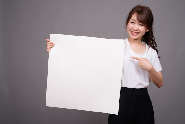 Femme asiatique montrant un tableau blanc vide avec copyspace