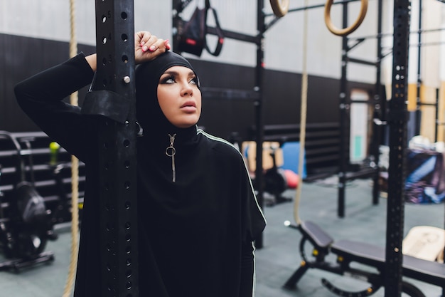 Femme asiatique musulmane en hijab exerçant dans une salle de sport.