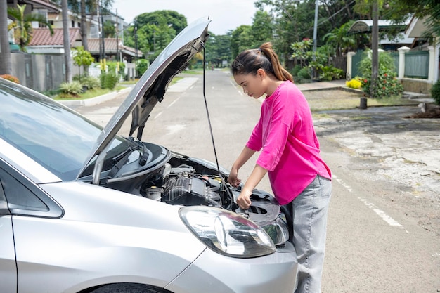 Femme asiatique ouvrant le capot de la voiture et cherchant des problèmes de voiture tombe en panne