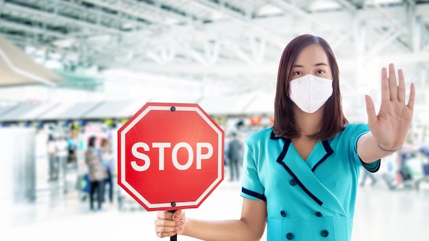 Une femme asiatique ouvre la main sur l'action d'arrêt et montre le panneau d'arrêt de la bannière pour le voyageur étranger sur la gare de l'aéroport