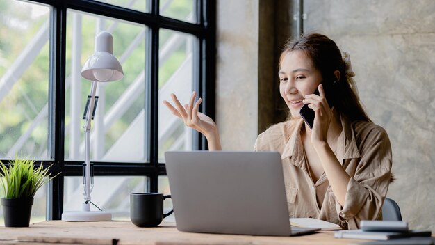 Femme asiatique parlant au téléphone, elle est vendeuse dans une start-up, elle appelle les clients pour vendre des produits et des promotions Concept de vente de produits par le biais de canaux téléphoniques