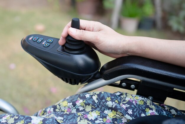 Femme asiatique patiente sur fauteuil roulant électrique avec joystick et télécommande à l'hôpital de soins infirmiers sain concept médical fort