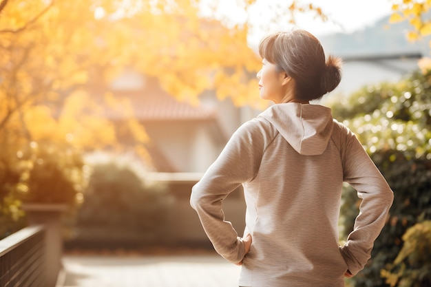 Femme asiatique plus âgée exerçant à l'extérieur avec le dos tourné