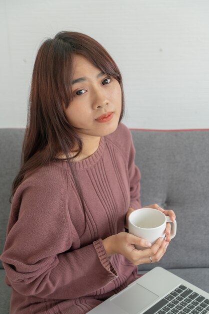 Femme asiatique, portable utilisation, sur, sofa, dans, salle de séjour