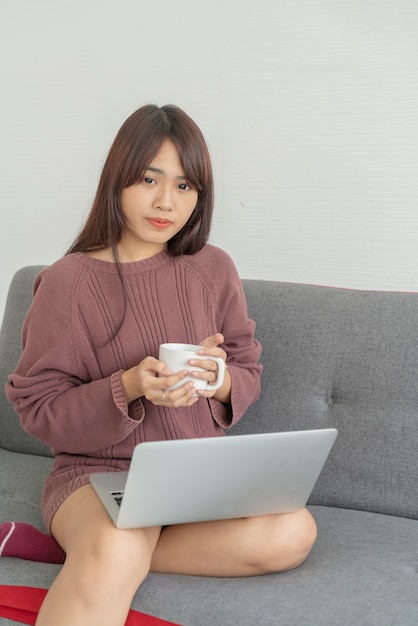 Femme asiatique, portable utilisation, sur, sofa, dans, salle de séjour