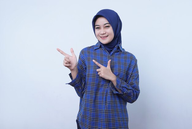 Femme asiatique portant le hijab noir souriant joyeusement avec un doigt pointé isolé sur fond de bannière blanc clair