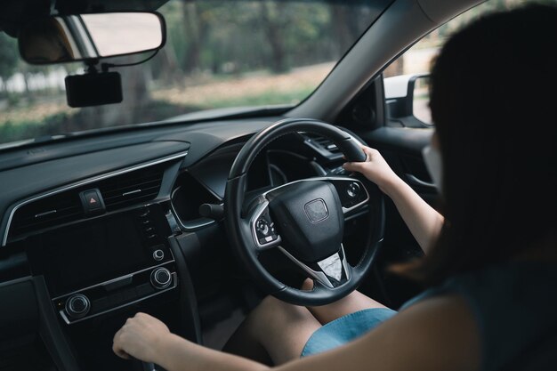 Femme asiatique portant un masque chirurgical en conduisant une voiture Pendant la pandémie de covid19 portant un masque lorsque vous conduisez une voiture allez à l'extérieur en quittant la maison