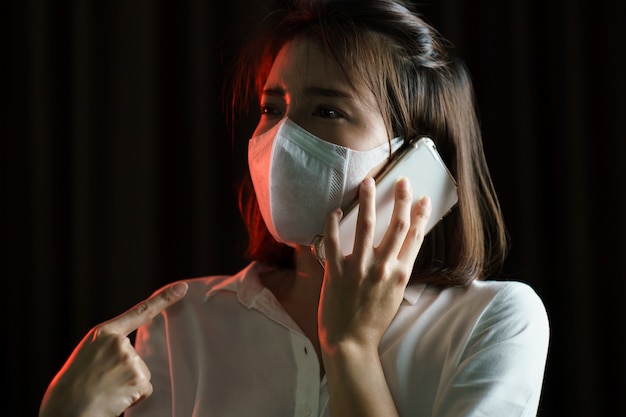 Femme asiatique portant un masque chirurgical et faisant un appel téléphonique