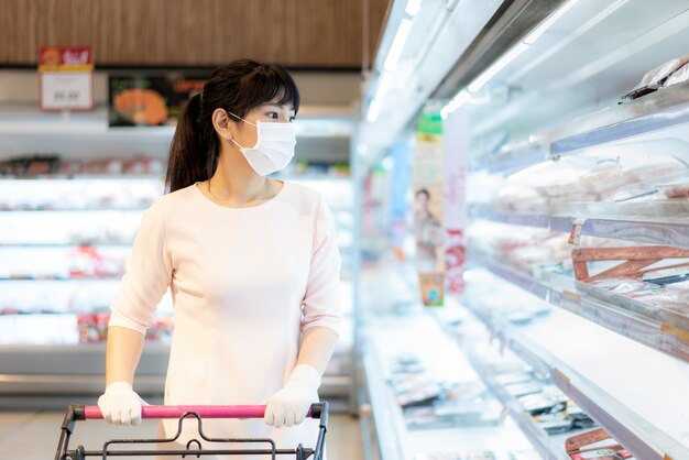 Femme asiatique portant un masque facial dans un supermarché