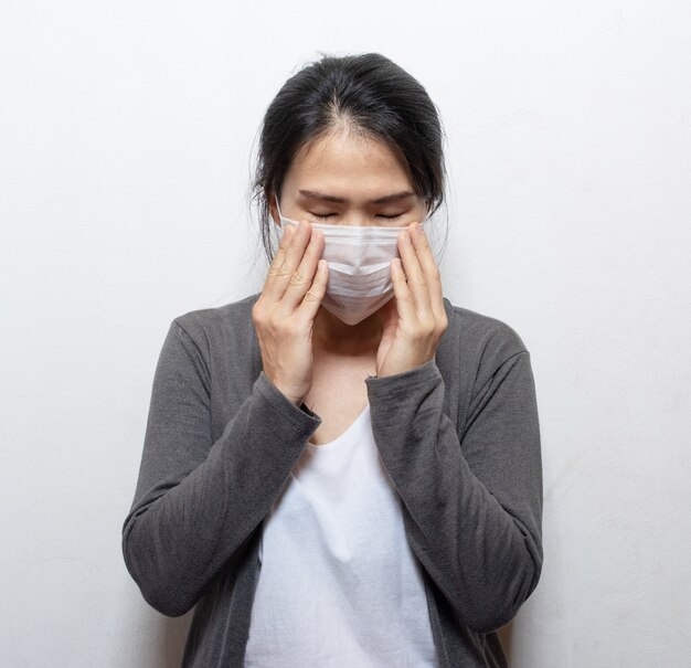 Femme asiatique portant un masque facial les mains couvrent le visage et les éternuements pour se protéger de la pollution de l'air