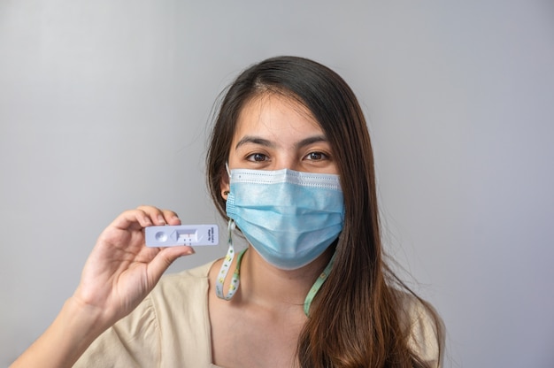 Femme asiatique portant un masque facial montrant un résultat négatif du kit de test rapide d'antigène à usage domestique. Pas d'infection au Covid-19, Coronavirus