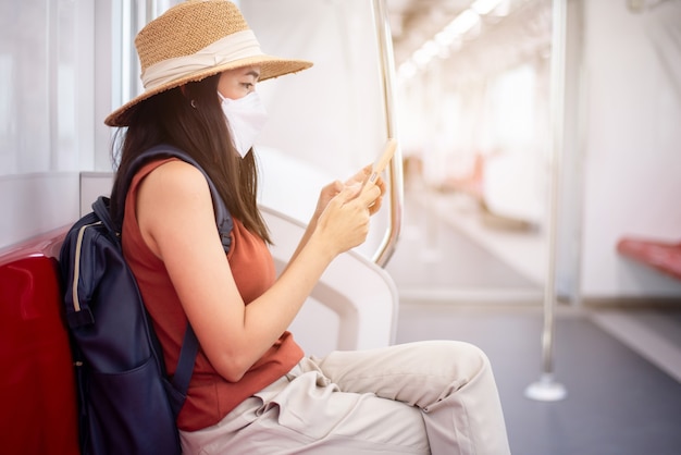 Femme asiatique portant un masque facial et utilisant un smartphone dans une rame de métro,Sécurité dans les transports publics,Nouvelle norme pendant la pandémie de covid-19