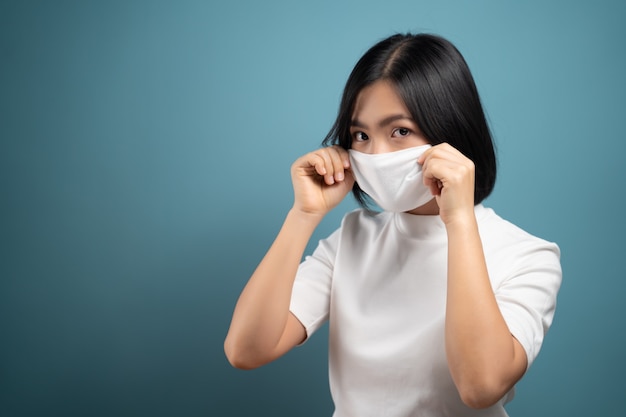 Femme asiatique portant un masque de protection pour la protection contre le virus et la maladie isolé sur bleu