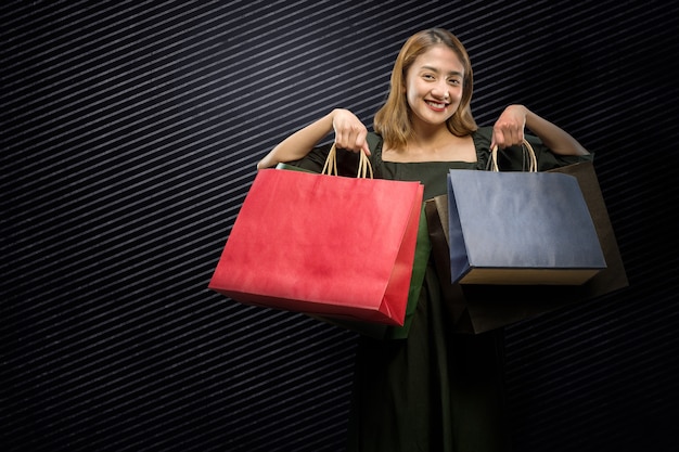 Femme asiatique portant un sac à provisions avec un fond noir. Concept de vendredi noir