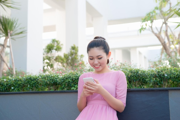 Femme asiatique portant des textos de vêtements traditionnels sur un smartphone
