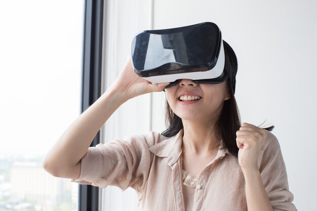 Une femme asiatique porte un casque vr et profite de l'expérience