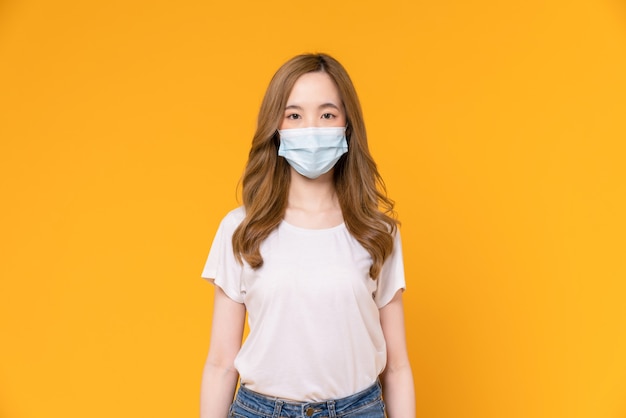 Une femme asiatique porte des masques pour protéger les maladies sur fond jaune.