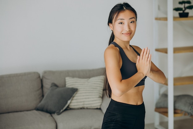 Femme asiatique pratique le yoga à la maison