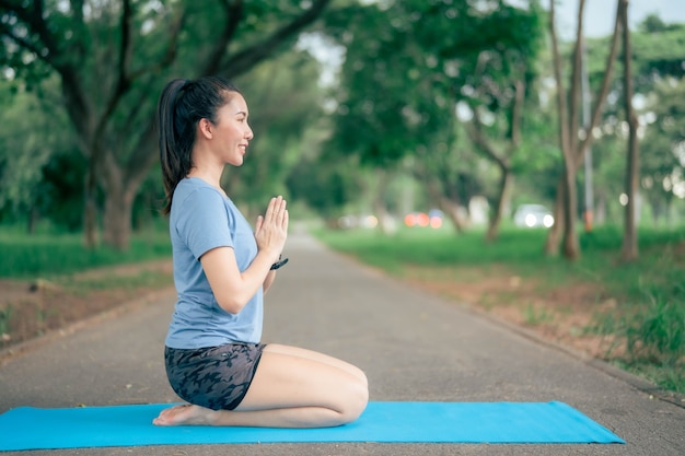 Une femme asiatique pratique le yoga et médite au parc. Mode de vie sain et concept de yoga.