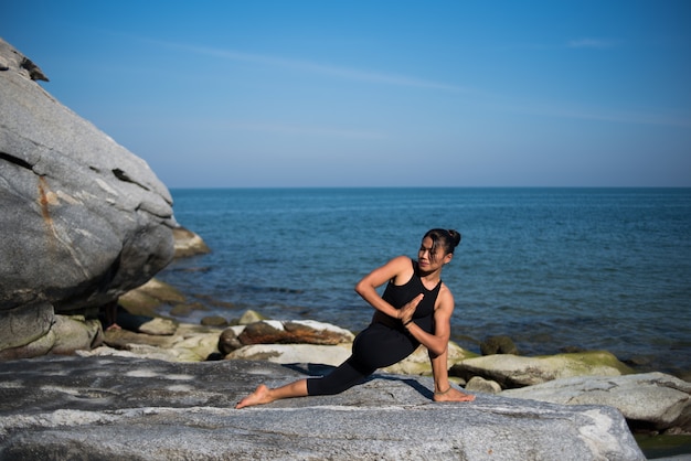 Femme asiatique pratique le yoga sur la plage