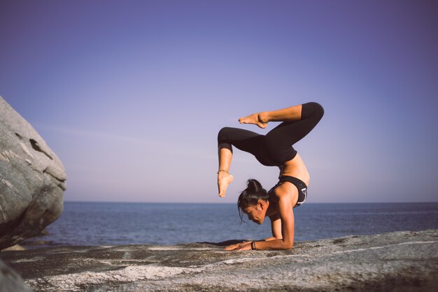 Femme asiatique pratique le yoga sur la plage