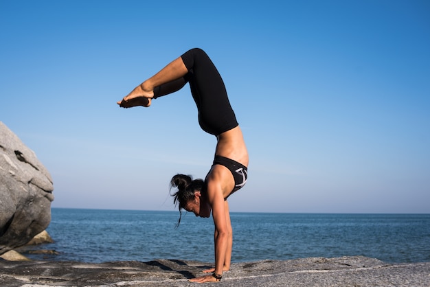 Femme asiatique pratique le yoga sur la plage